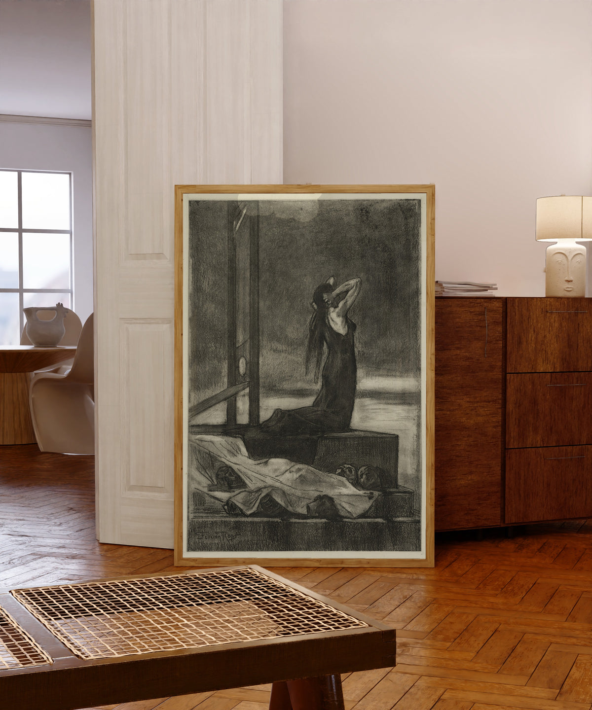 Framed art print of Capital Punishment: The Pain of Death by Félicien Rops, in a light wood frame leaning in a warm room with a parquet floor