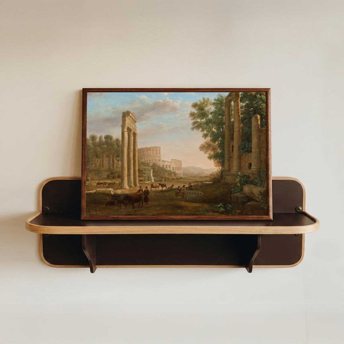 Framed art print of Capriccio with Ruins of the Roman Forum by Claude Lorrain, in a dark wood frame resting on a wall shelf