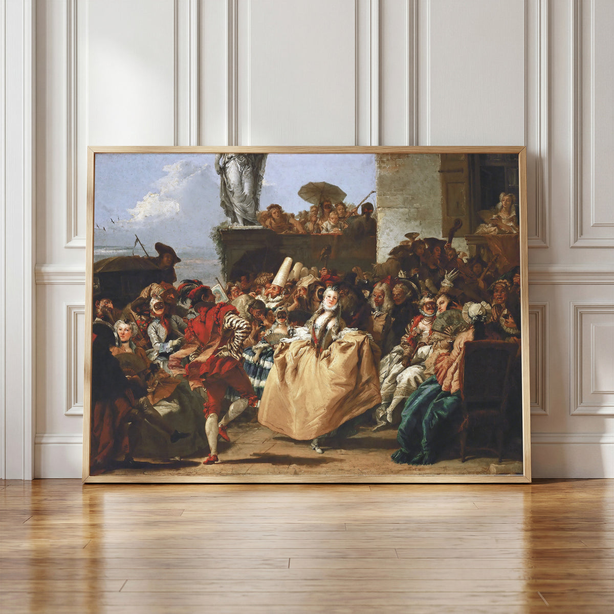 Framed art print of Carnival Scene (The Minuet) by Giovanni Domenico Tiepolo, in a light wood frame leaning against a panelled white wall