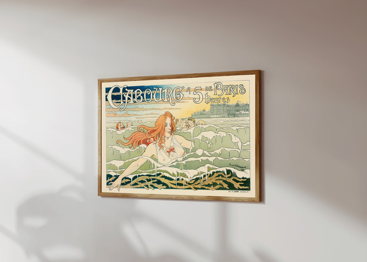 Framed art print of Casino de Cabourg by Henri Privat-Livemont, in a light wood frame on a sunlit white wall, seen at a slight angle