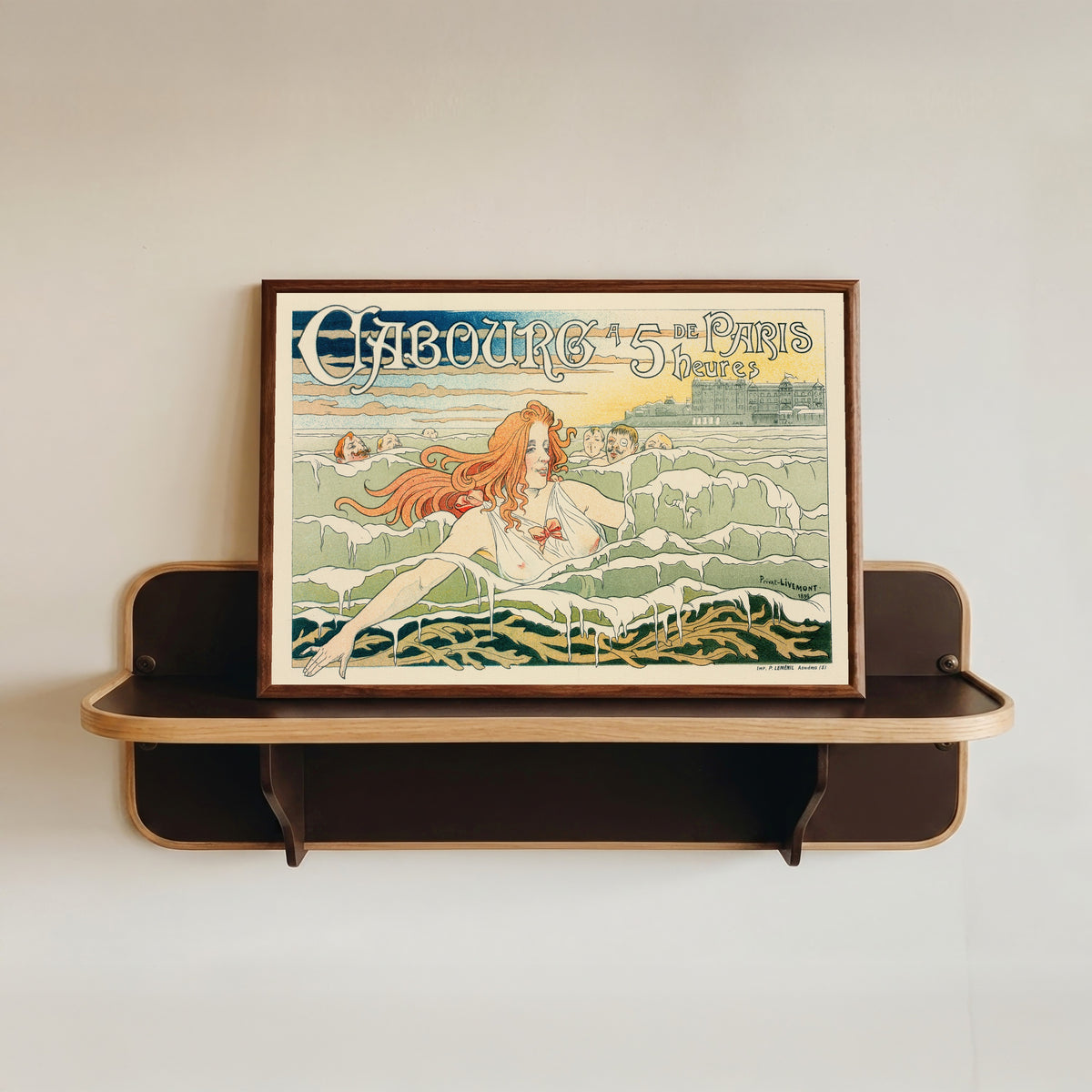Framed art print of Casino de Cabourg by Henri Privat-Livemont, in a dark wood frame resting on a wall shelf