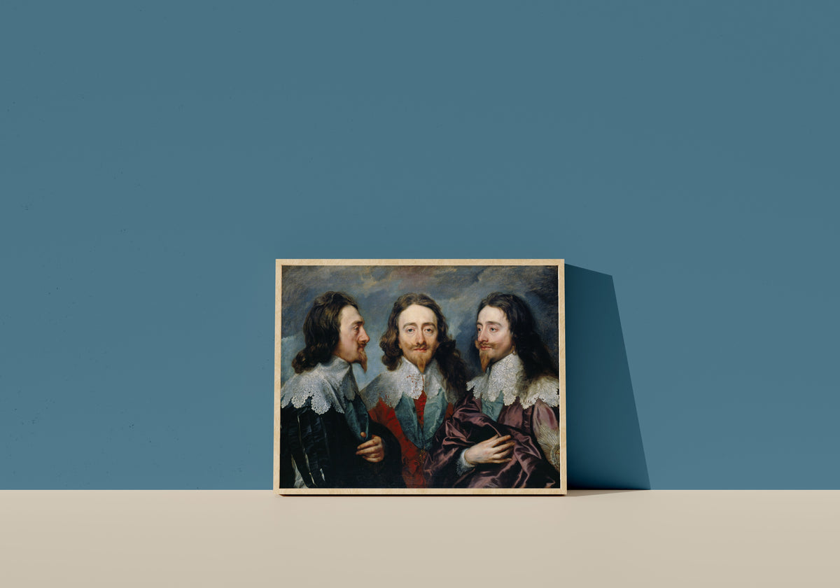 Framed art print of Charles I in Three Positions by Anthony van Dyck, in a light wood frame leaning on a blue wall