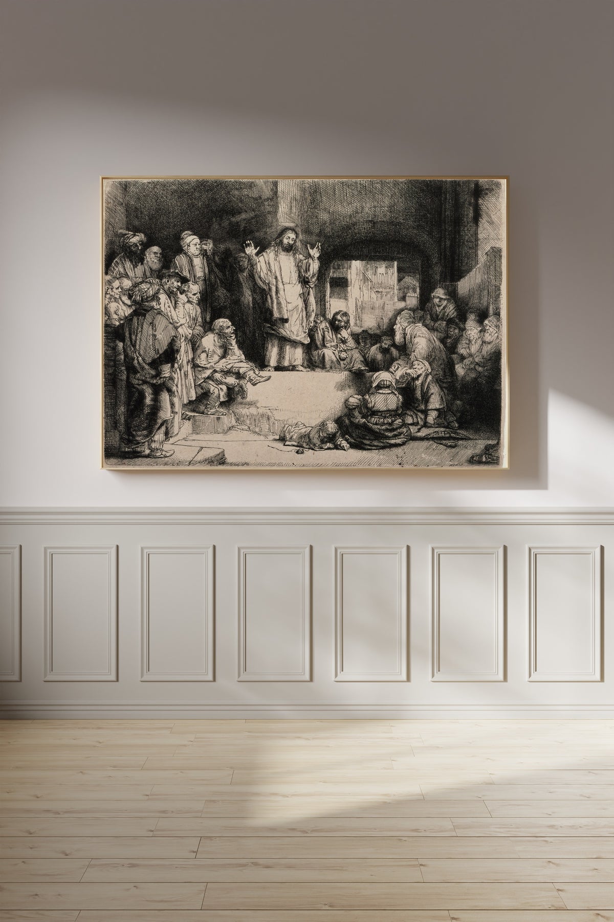 Framed art print of Christ Preaching, called La Petite Tombe by Rembrandt van Rijn, on a panelled wall in afternoon light