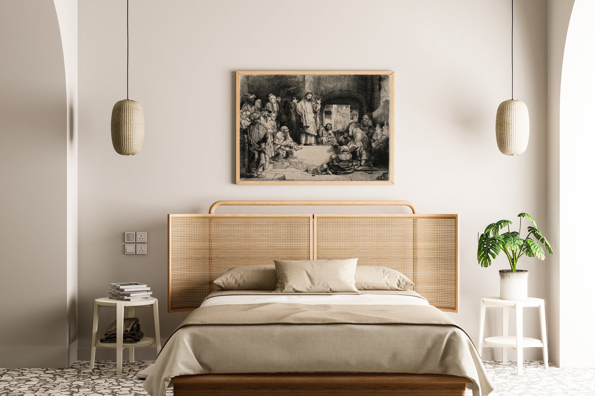 Framed art print of Christ Preaching, called La Petite Tombe by Rembrandt van Rijn, above a cane-headboard bed