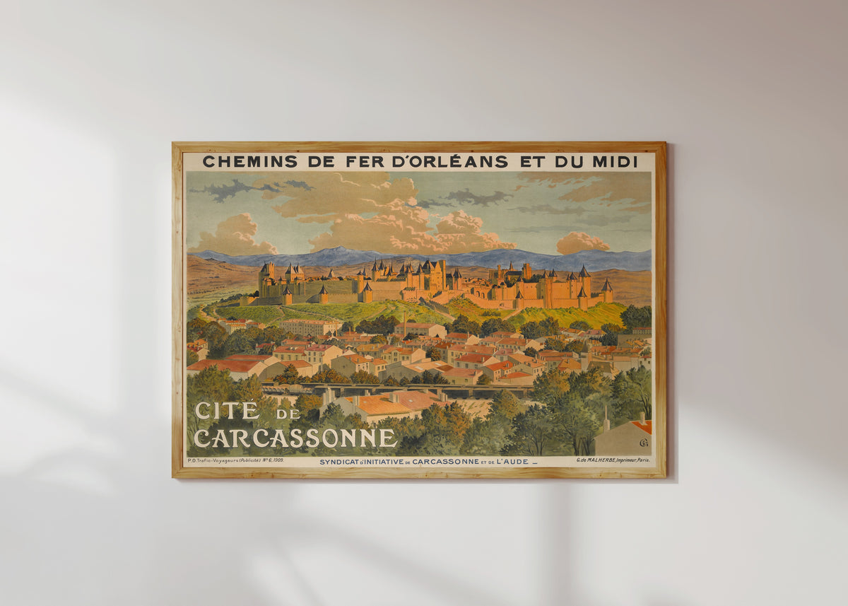 Framed art print of Cité de Carcassonne by Eugène Grasset, in a light wood frame on a sunlit white wall