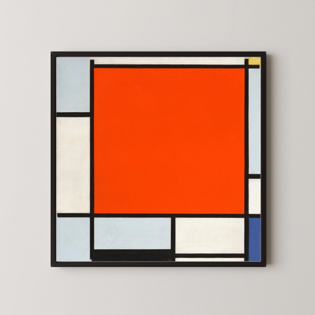 Framed art print of Composition with Large Red Plane, Bluish Gray, Yellow, Black and Blue by Piet Mondrian, in a black frame on a pale wall