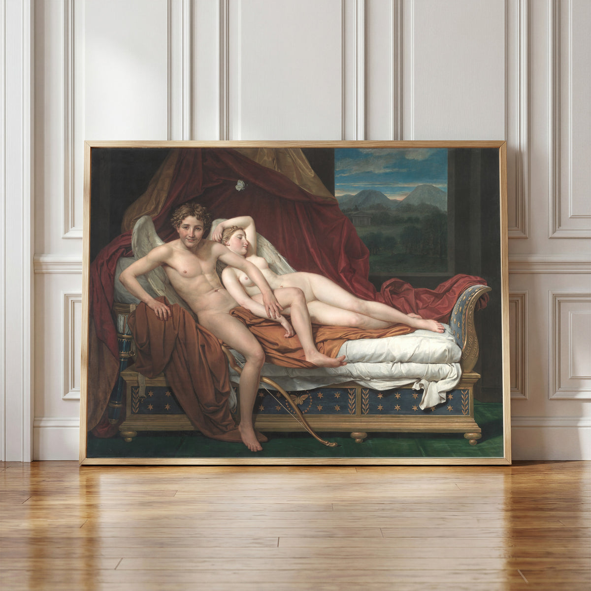 Framed art print of Cupid and Psyche by Jacques-Louis David, in a light wood frame leaning against a panelled white wall