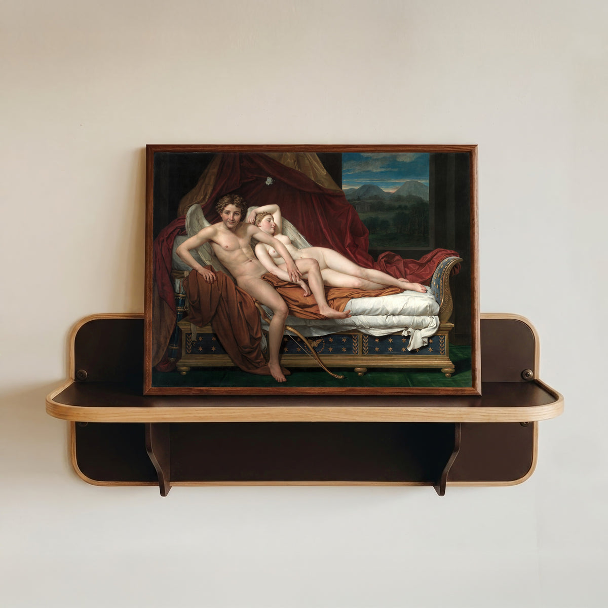 Framed art print of Cupid and Psyche by Jacques-Louis David, in a dark wood frame resting on a wall shelf