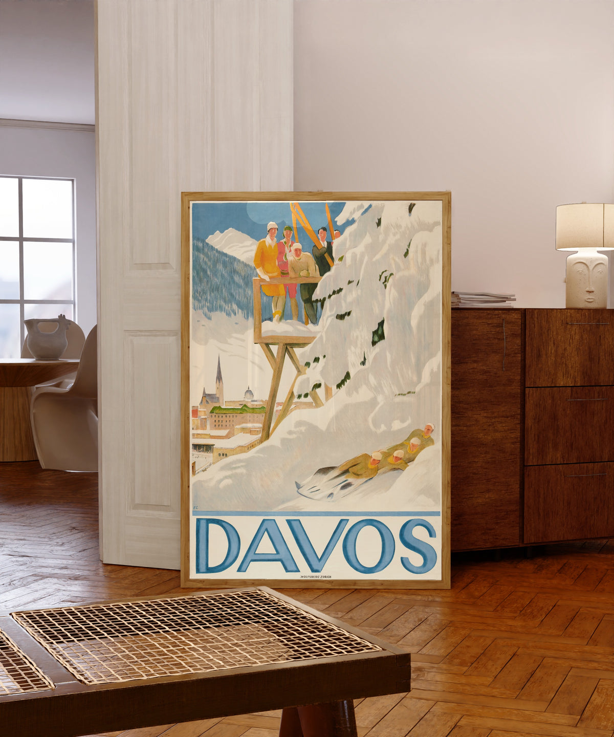 Framed art print of Davos by Emil Cardinaux, in a light wood frame leaning in a warm room with a parquet floor