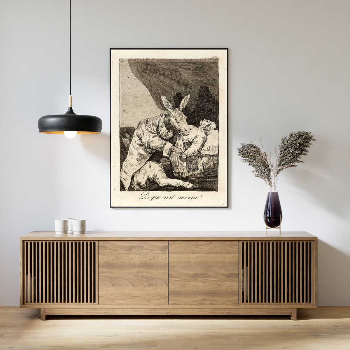 Framed art print of De que mal morira? (Of What Ill Will He Die?), Los Caprichos, Plate 40 by Francisco de Goya, above a slatted wood sideboard