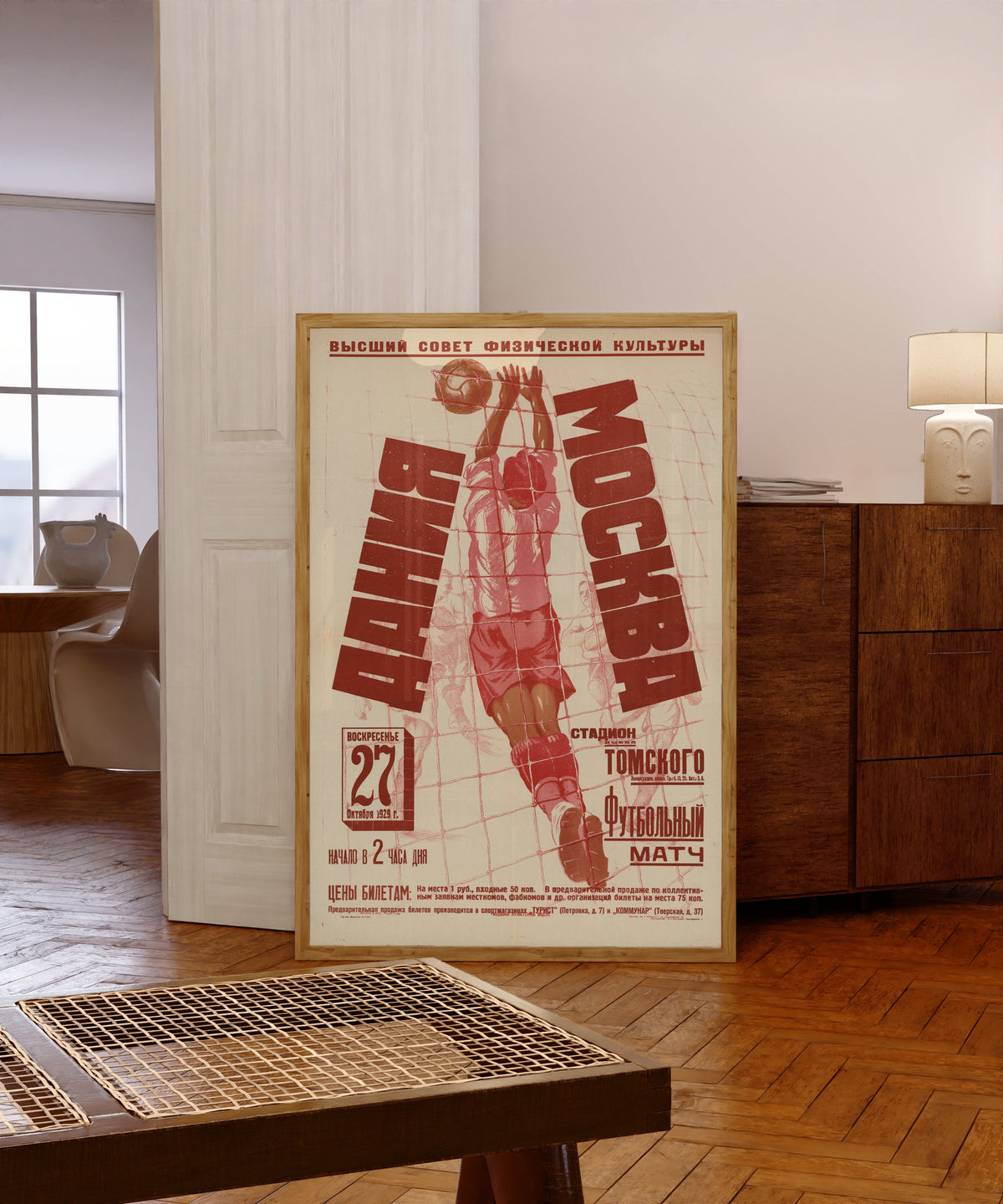 Framed art print of Denmark v. Moscow: Football Match, 1929, in a light wood frame leaning in a warm room with a parquet floor