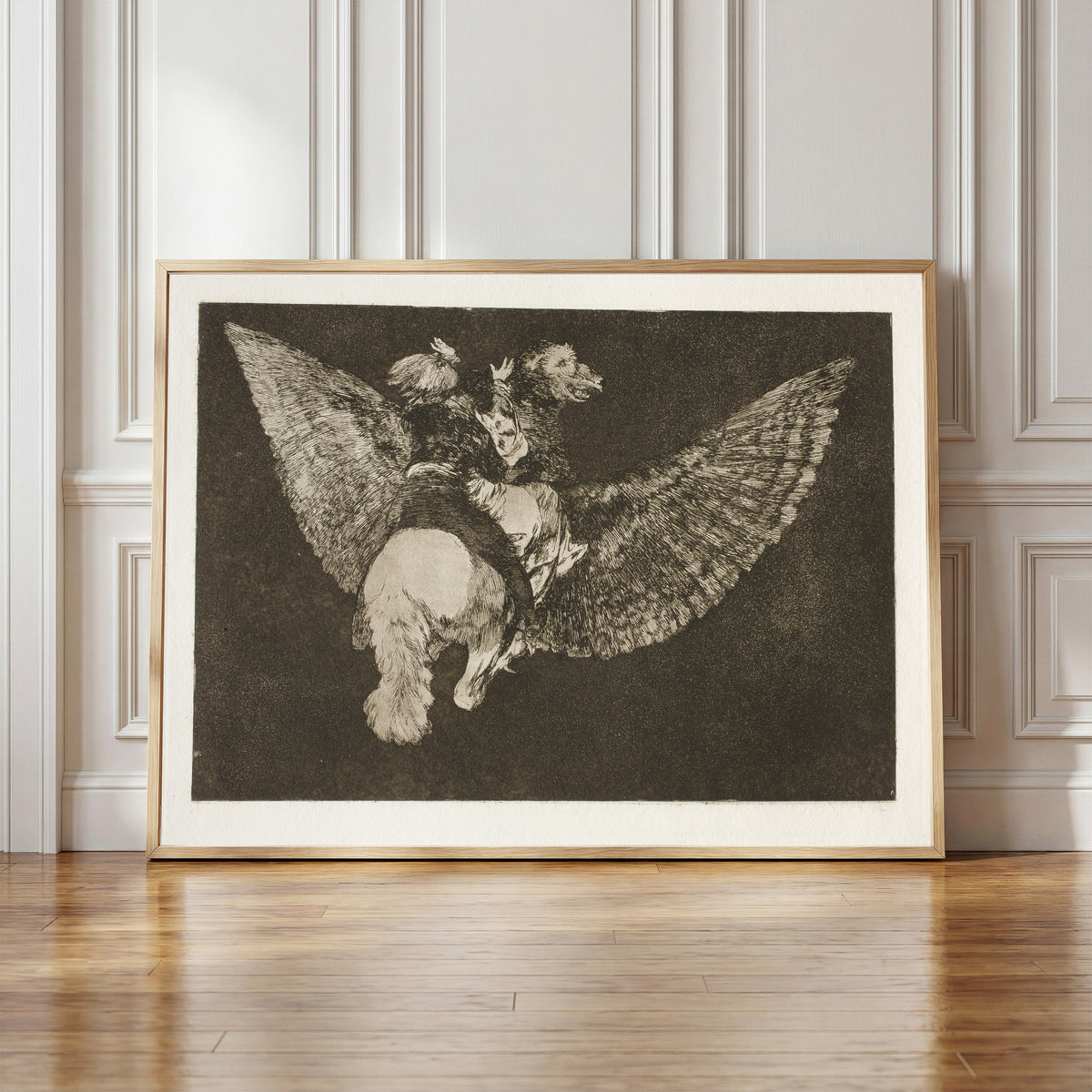 Framed art print of Disparate volante (Flying Folly), from Los Disparates by Francisco de Goya, in a light wood frame leaning against a panelled white wall