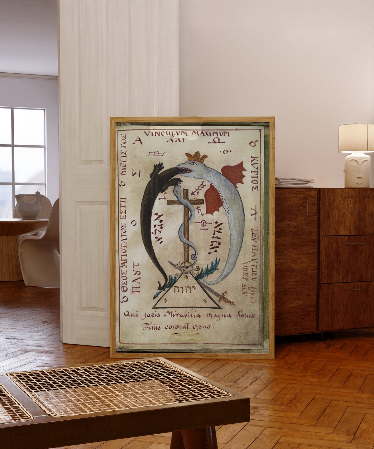 Framed art print of Dragon Devouring a Lizard, from Cyprianus by Unknown artist, in a light wood frame leaning in a warm room with a parquet floor