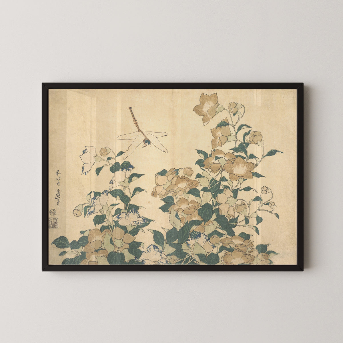Framed art print of Dragonfly and Bellflower by Katsushika Hokusai, in a black frame on a pale wall