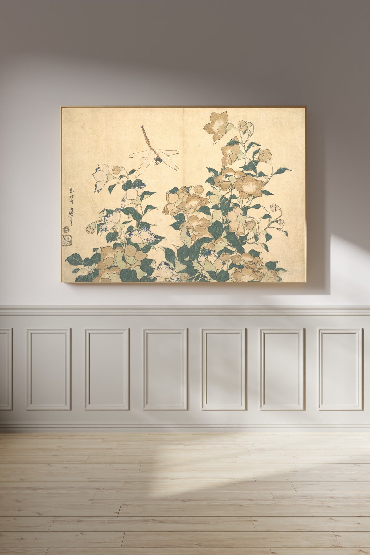 Framed art print of Dragonfly and Bellflower by Katsushika Hokusai, on a panelled wall in afternoon light