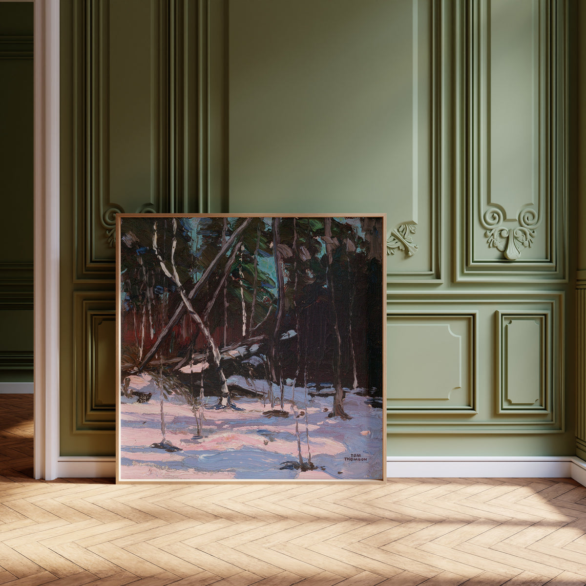 Framed art print of Early Snow, Algonquin Park by Tom Thomson, leaning against olive-green panelling on a herringbone floor