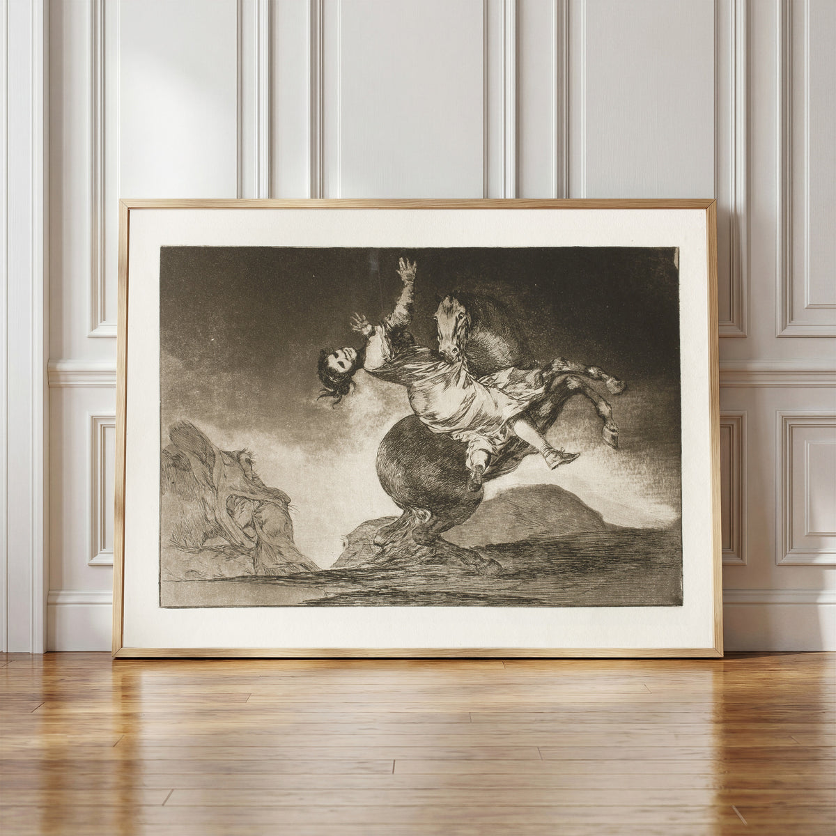 Framed art print of El caballo raptor (The Horse Abductor), from Los… by Francisco de Goya, in a light wood frame leaning against a panelled white wall