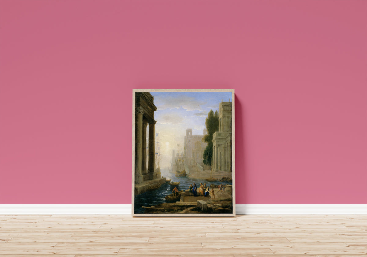 Framed art print of Embarkation of St Paula by Claude Lorrain, in a light wood frame leaning on a pink wall above a wooden floor