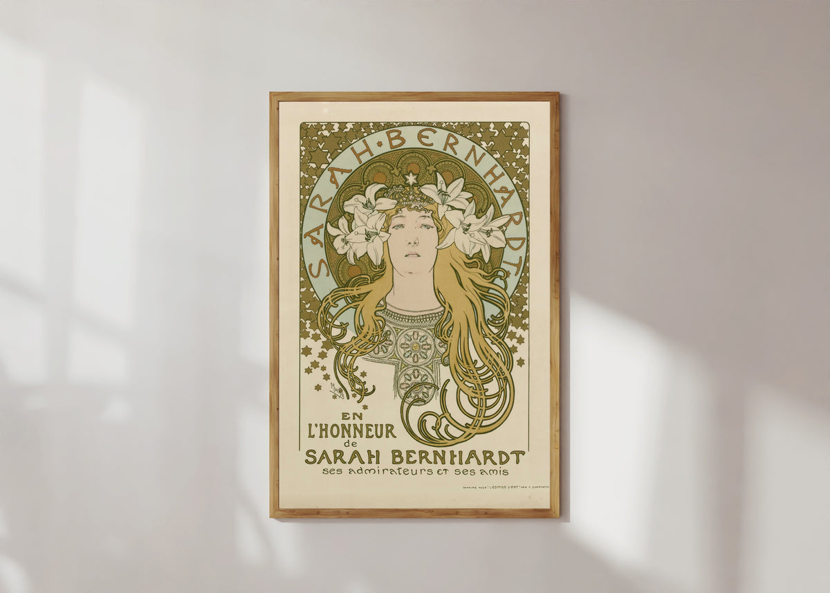 Framed art print of En l’honneur de Sarah Bernhardt, ses admirateurs et ses amis by Alphonse Mucha, in a light wood frame on a sunlit white wall