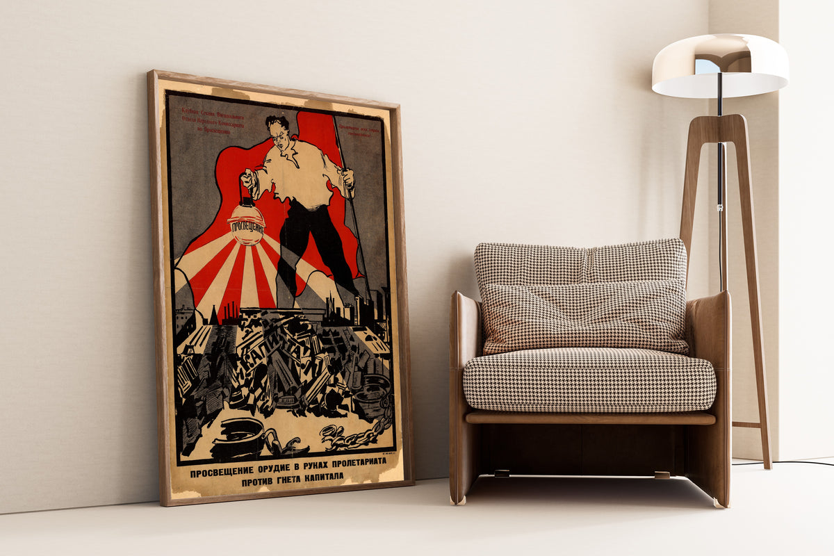 Framed art print of Enlightenment Is a Weapon in the Hands of the Proletariat, leaning against a wall beside an armchair and a floor lamp