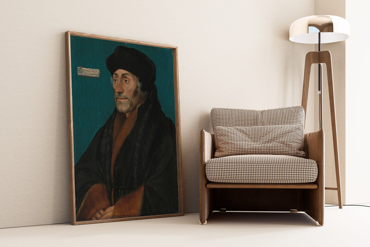 Framed art print of Erasmus of Rotterdam by Hans Holbein the Younger, leaning against a wall beside an armchair and a floor lamp