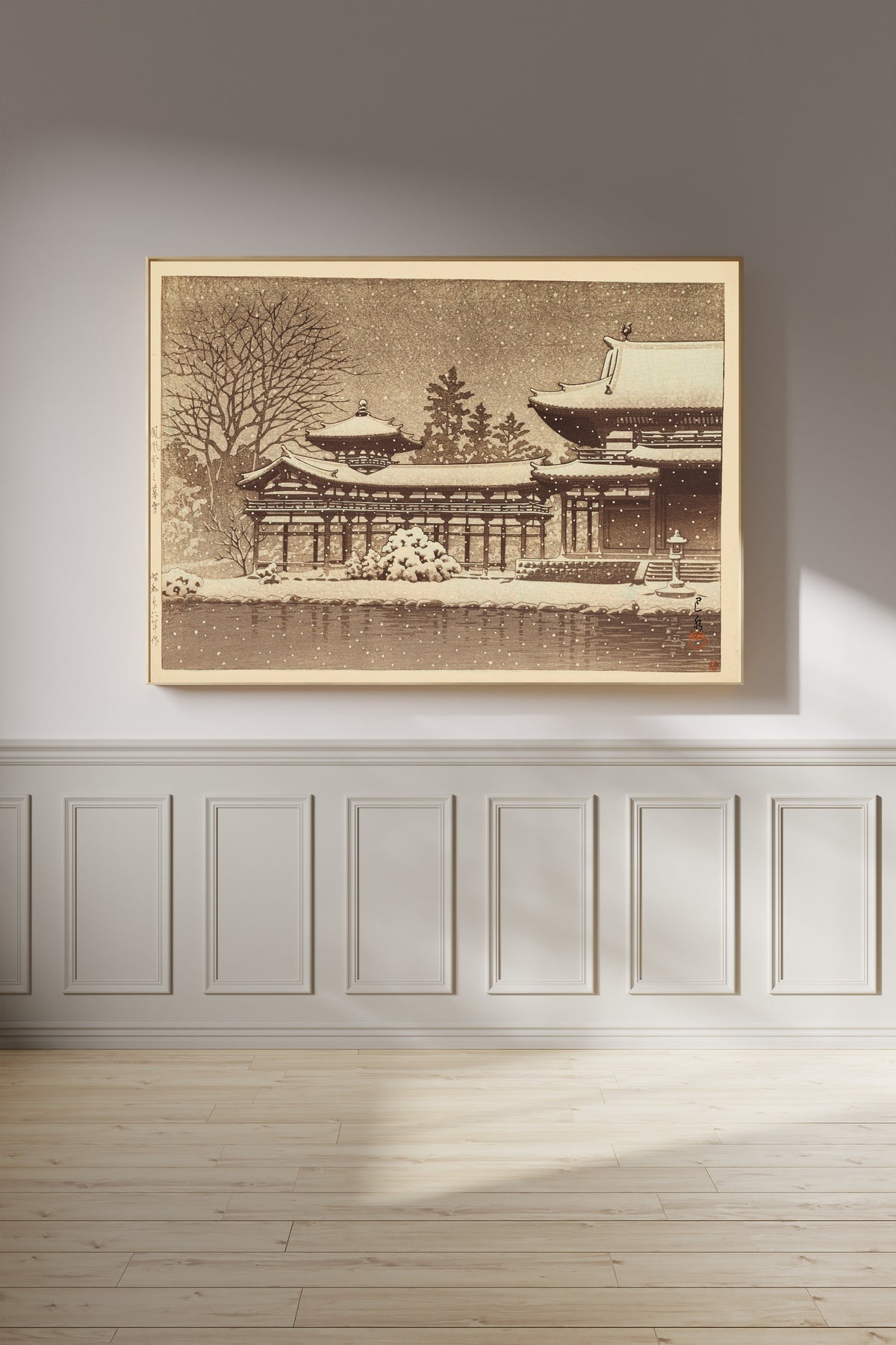 Framed art print of Evening Snow at Phoenix Hall by Kawase Hasui, on a panelled wall in afternoon light