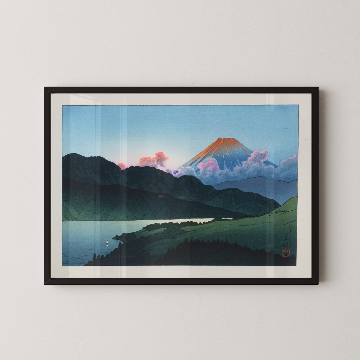 Framed art print of Evening of Mount Fuji from Lake Ashino-ko by Kawase Hasui, in a black frame on a pale wall