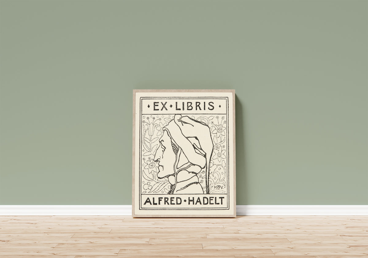 Framed art print of Ex Libris Alfred Hadelt by Heinrich Vogeler, in a light wood frame leaning on a sage green wall above a wooden floor