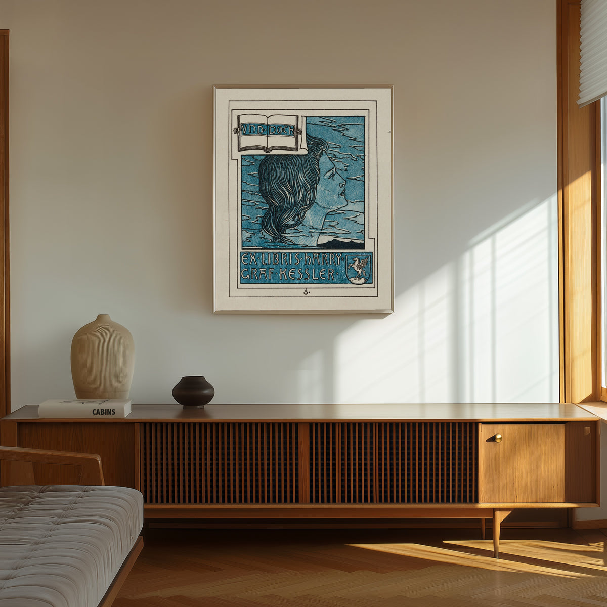 Framed art print of Ex Libris Harry Graf Kessler by Joseph Sattler, in a thin light frame on a sunlit wall above a wooden sideboard