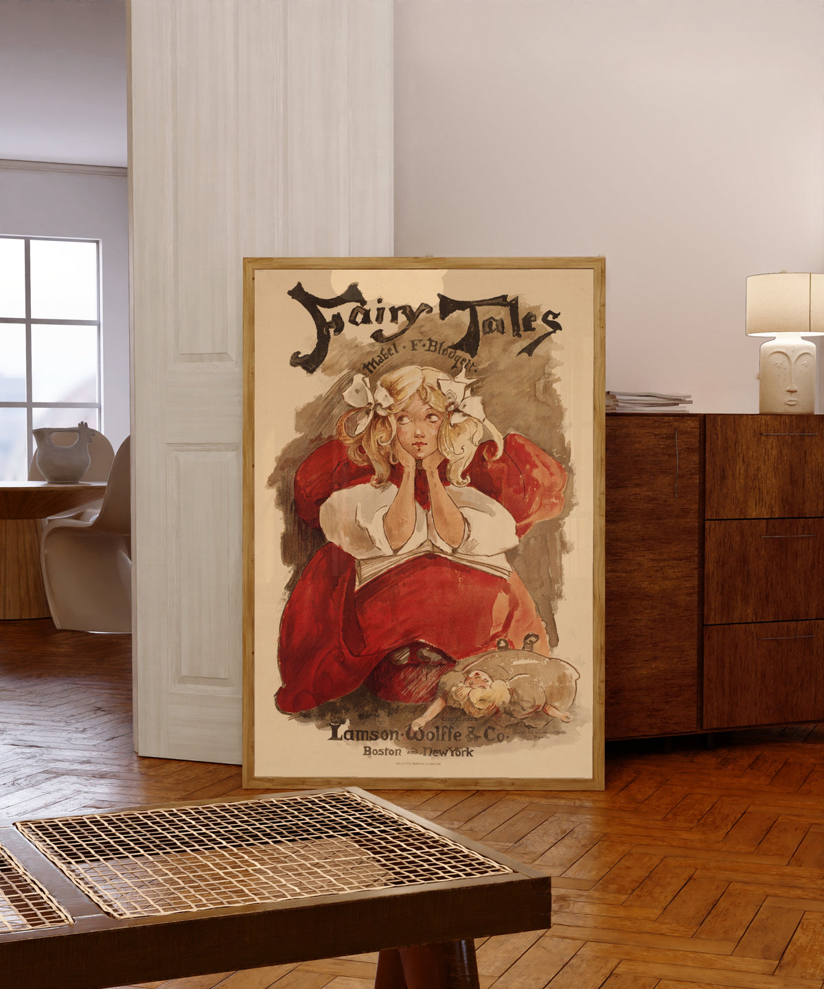 Framed art print of Fairy Tales by Mabel F. Blodgett by Ethel Reed, in a light wood frame leaning in a warm room with a parquet floor