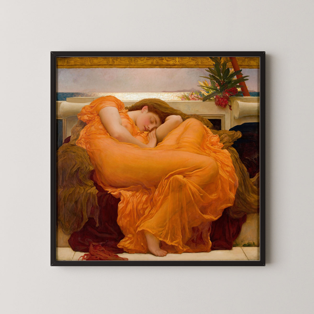 Framed art print of Flaming June by Frederic Leighton, in a black frame on a pale wall