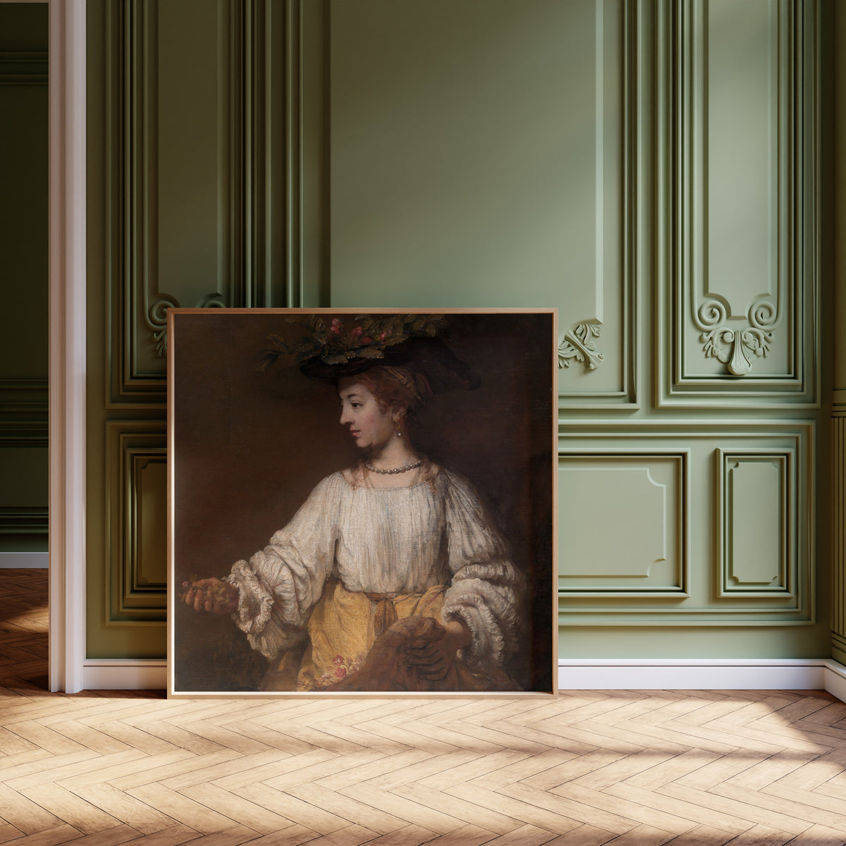 Framed art print of Flora by Rembrandt van Rijn, leaning against olive-green panelling on a herringbone floor