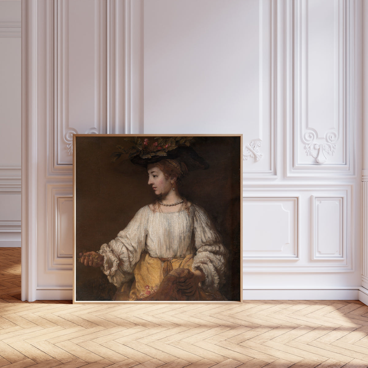Framed art print of Flora by Rembrandt van Rijn, leaning against pale pink panelling on a herringbone floor