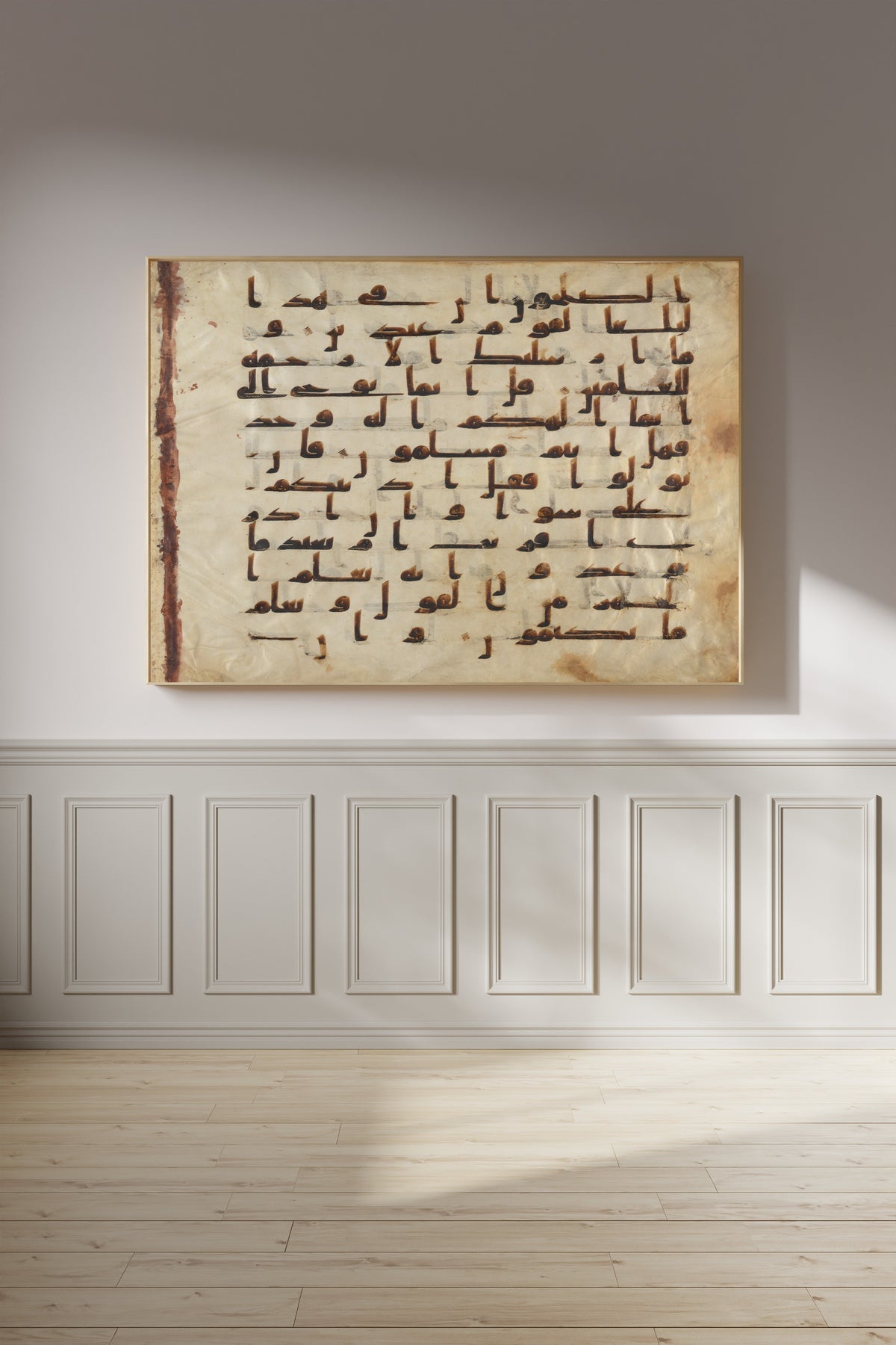 Framed art print of Folio from the Tashkent Qur'an, on a panelled wall in afternoon light
