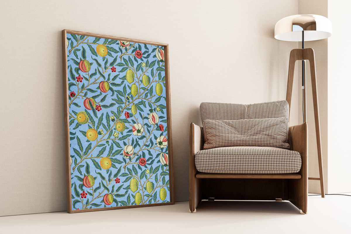 Framed art print of Four Fruits by William Morris, leaning against a wall beside an armchair and a floor lamp