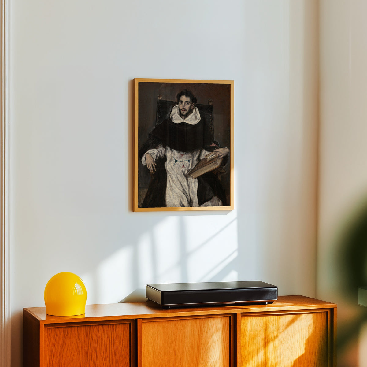 Framed art print of Fray Hortensio Félix Paravicino by El Greco, in a light wood frame on a white wall above an orange sideboard