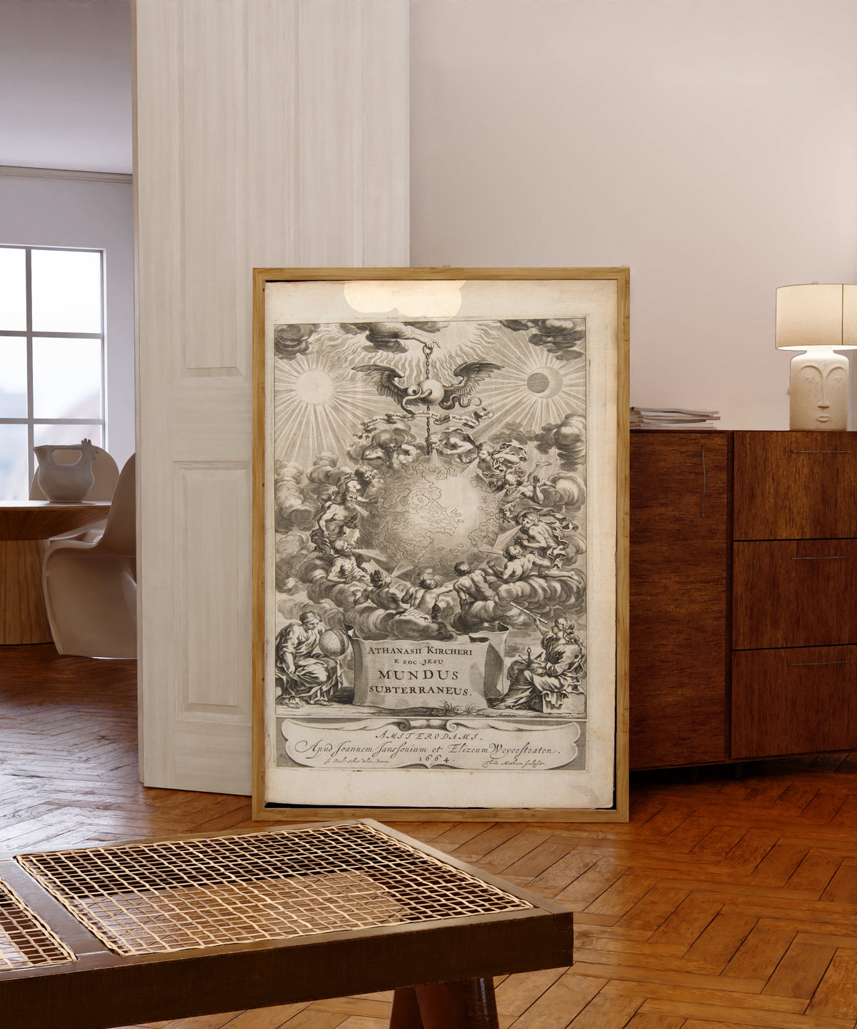Framed art print of Frontispiece of Mundus Subterraneus, Volume 1 by Athanasius Kircher, in a light wood frame leaning in a warm room with a parquet floor