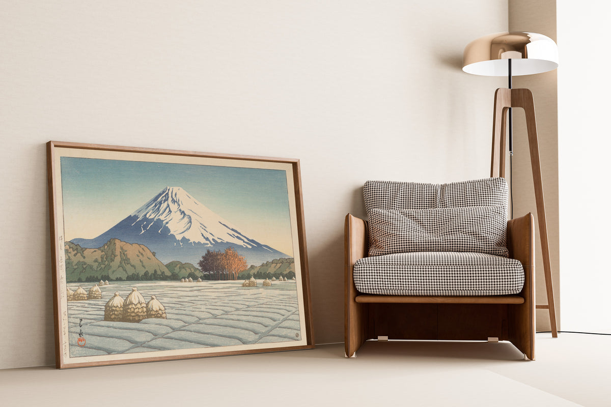 Framed art print of Frosty Morning in Nagaoka, Izu by Kawase Hasui, leaning against a wall beside an armchair and a floor lamp
