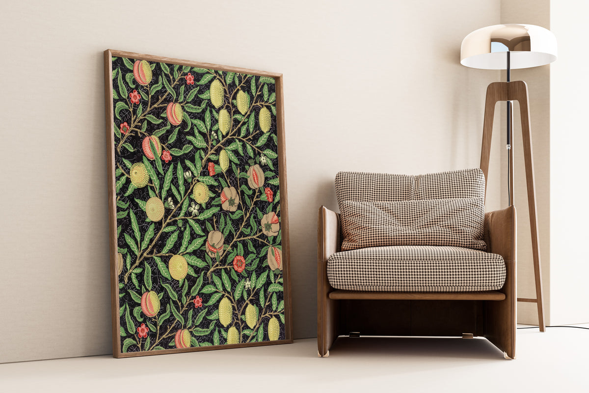 Framed art print of Fruit by William Morris, leaning against a wall beside an armchair and a floor lamp