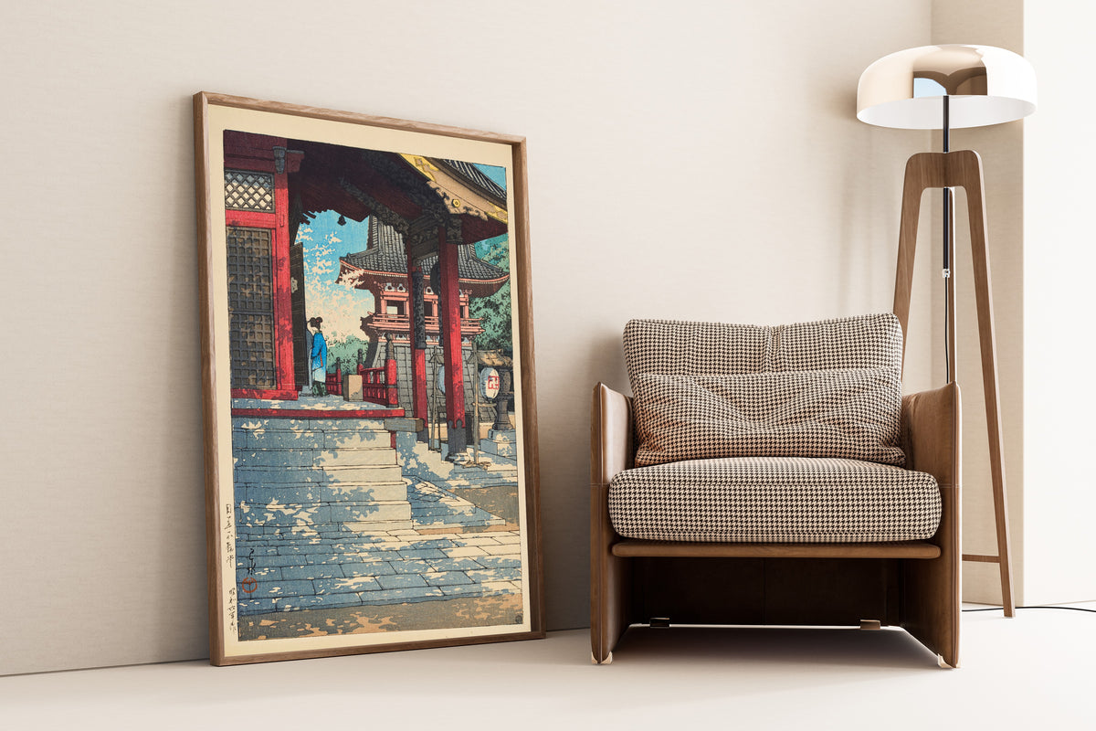Framed art print of Fudo Hall in Meguro by Kawase Hasui, leaning against a wall beside an armchair and a floor lamp