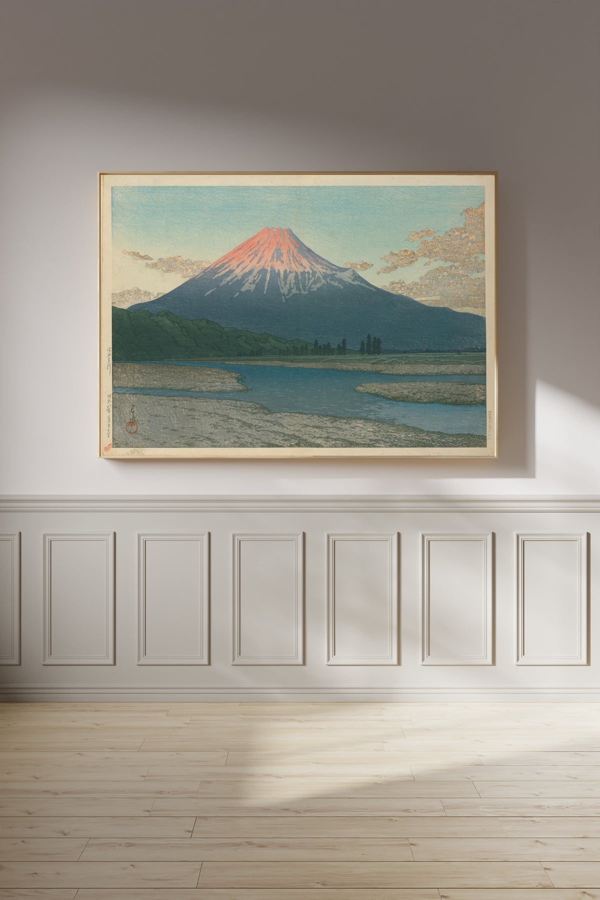 Framed art print of Fuji River by Kawase Hasui, on a panelled wall in afternoon light