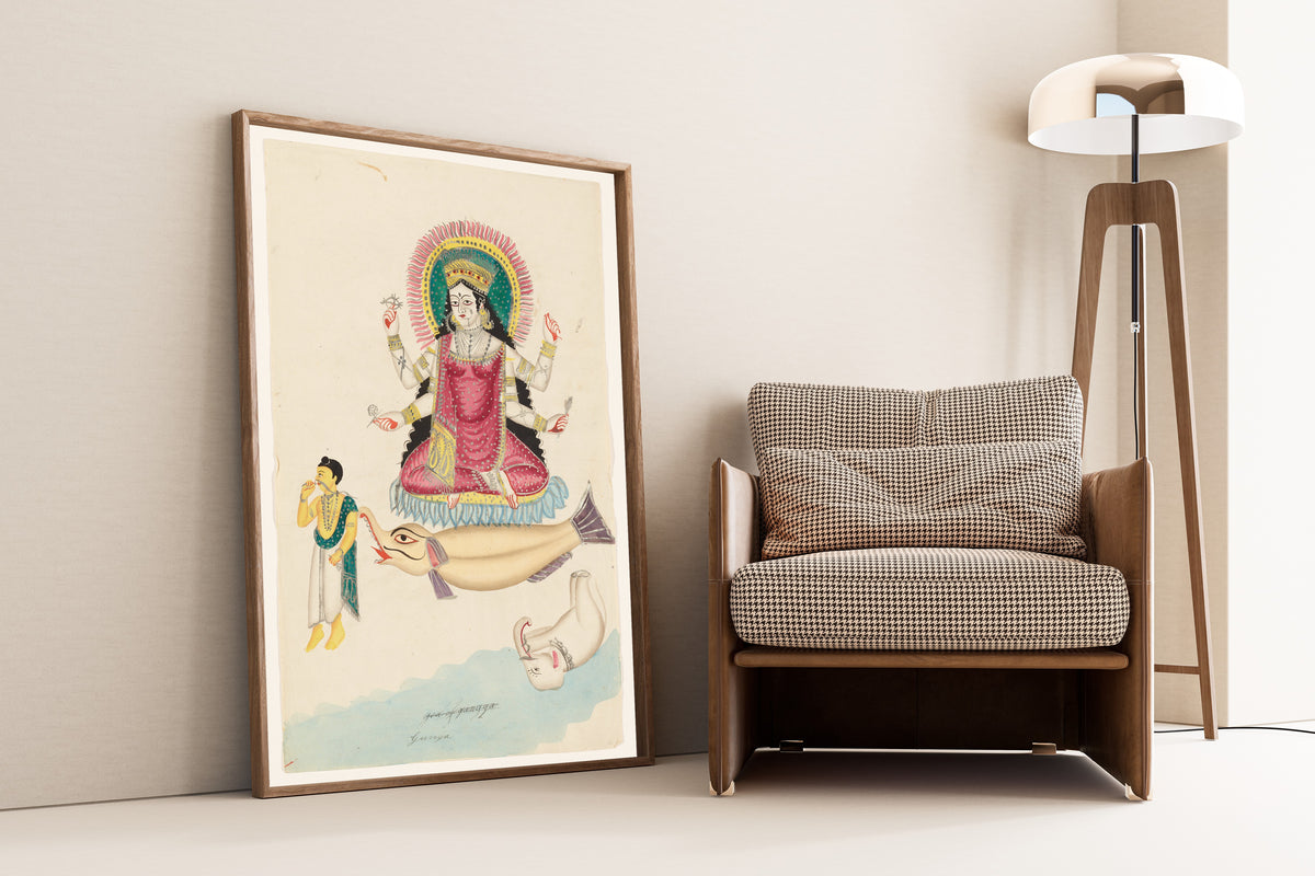 Framed art print of Ganga on a Crocodile by Kalighat painter, leaning against a wall beside an armchair and a floor lamp