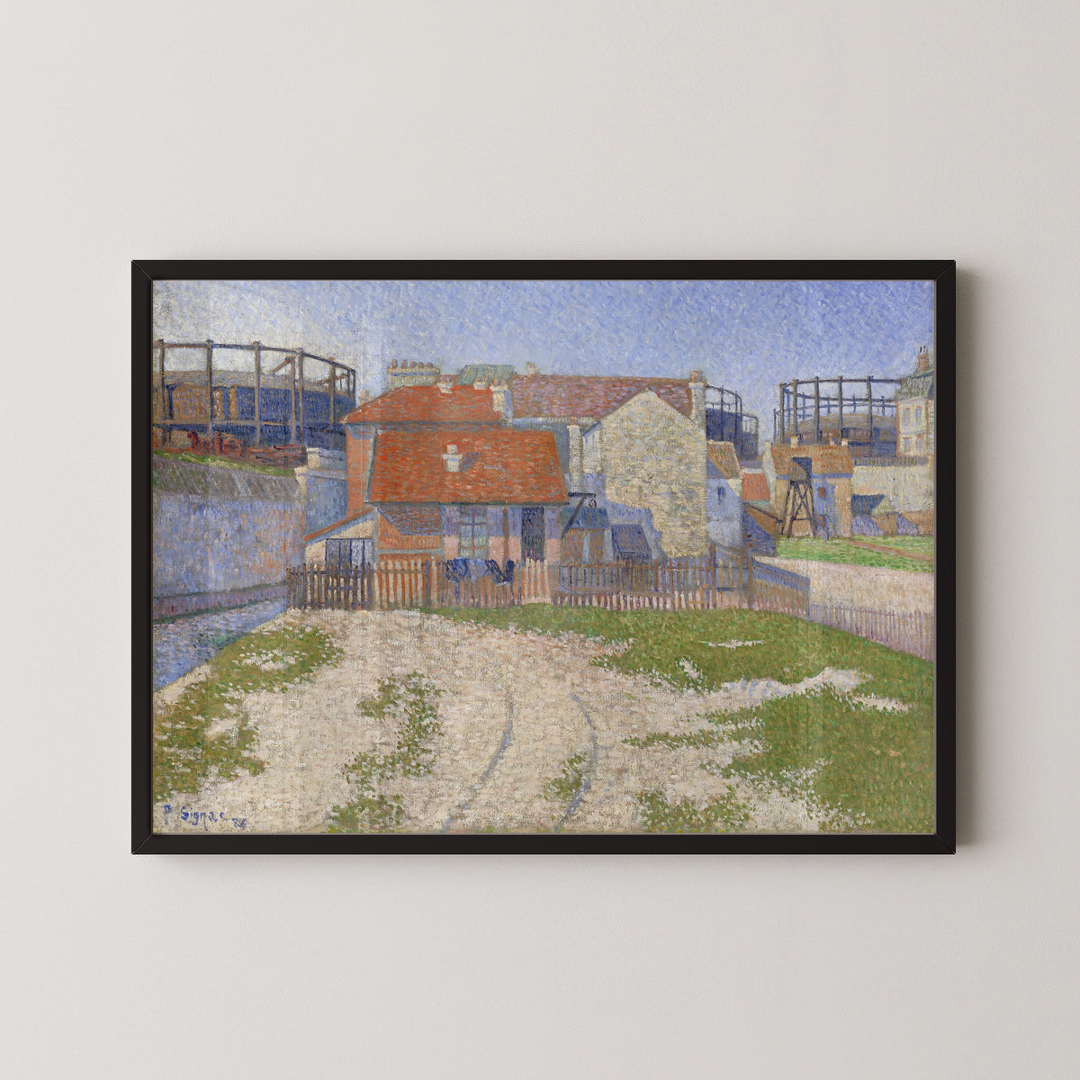 Framed art print of Gasometers at Clichy by Paul Signac, in a black frame on a pale wall
