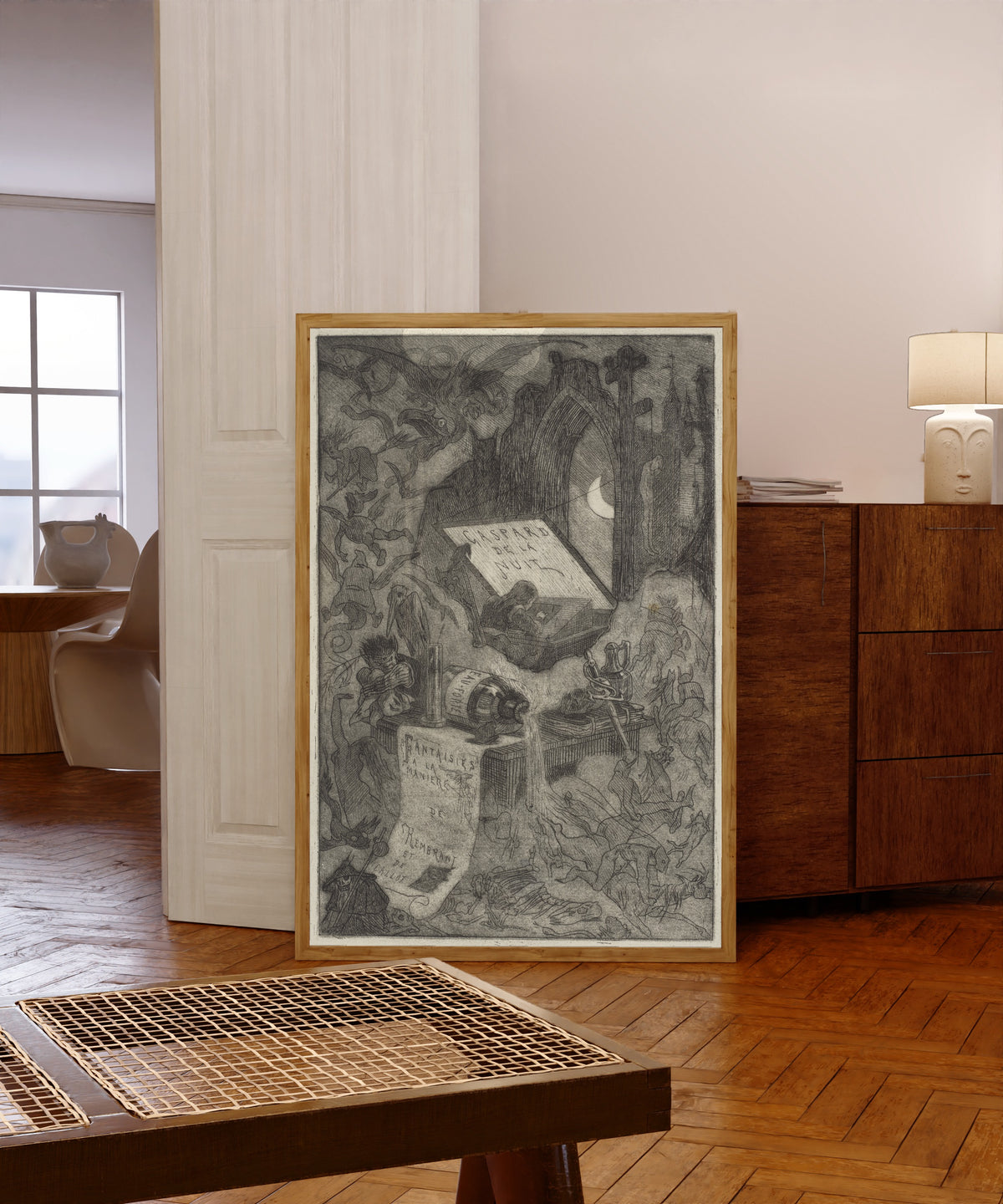 Framed art print of Gaspard de la Nuit by Félicien Rops, in a light wood frame leaning in a warm room with a parquet floor