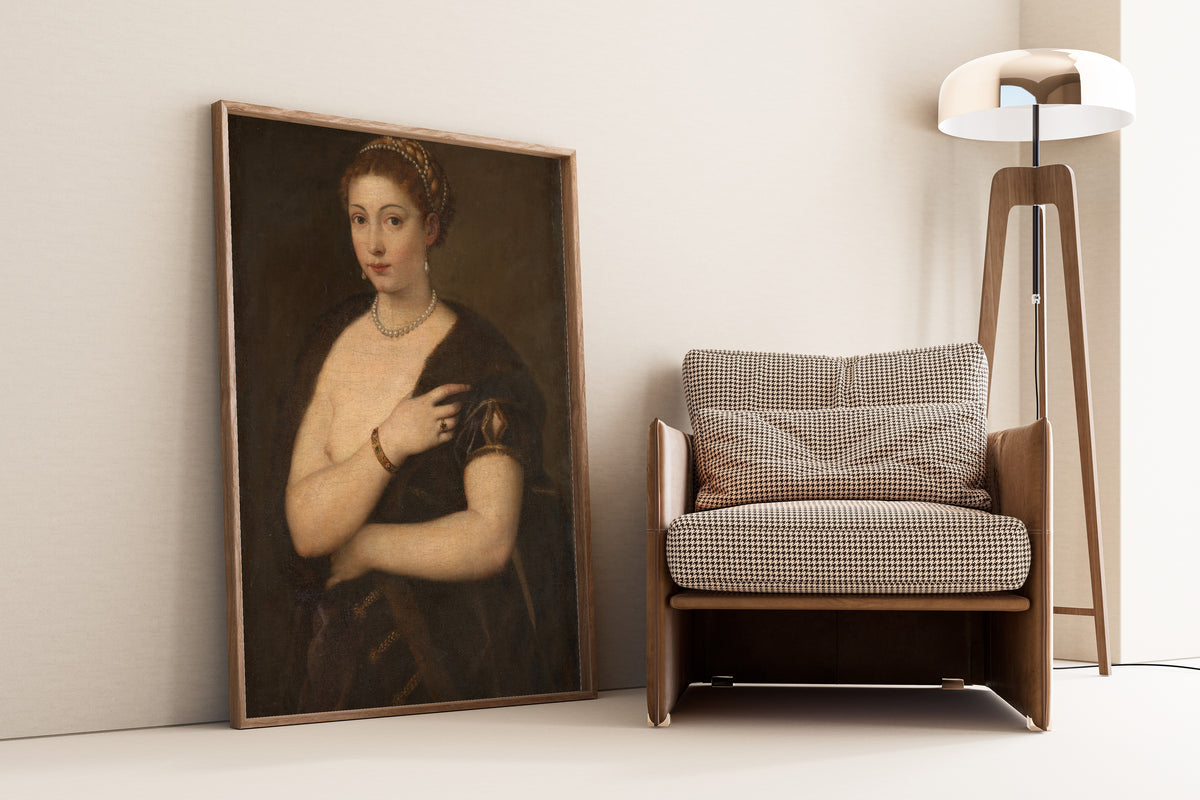 Framed art print of Girl in a Fur by Titian, leaning against a wall beside an armchair and a floor lamp