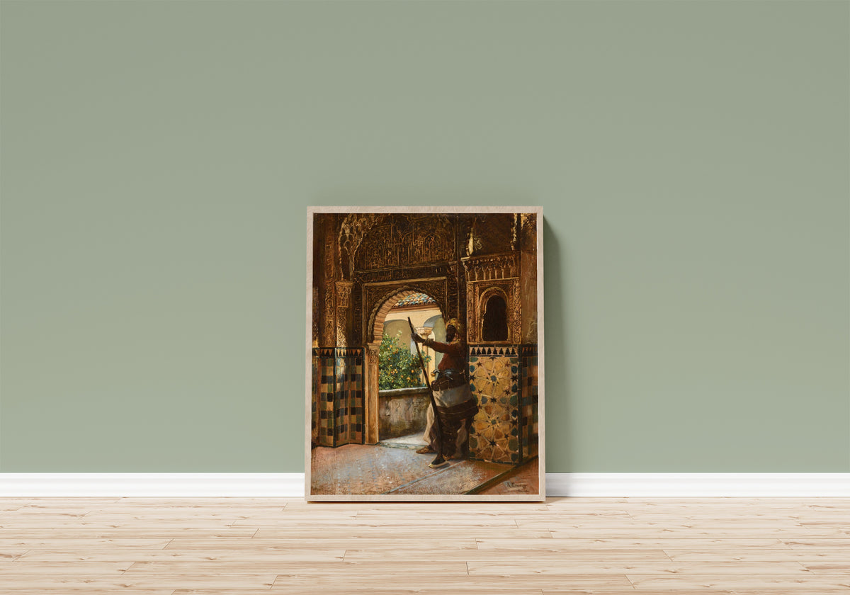 Framed art print of Guarding the Alhambra by Rudolf Ernst, in a light wood frame leaning on a sage green wall above a wooden floor