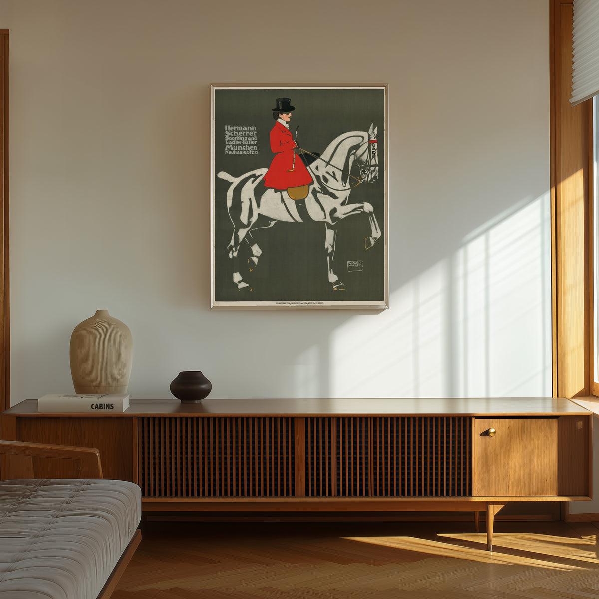 Framed art print of Hermann Scherrer: Sporting and Ladies-Tailor, München by Ludwig Hohlwein, in a thin light frame on a sunlit wall above a wooden sideboard