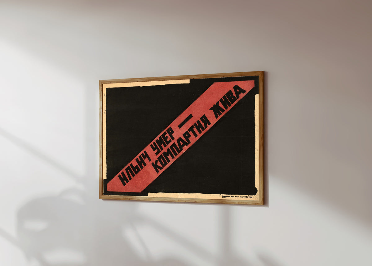 Framed art print of Ilyich is dead, the Communist Party lives, in a light wood frame on a sunlit white wall, seen at a slight angle