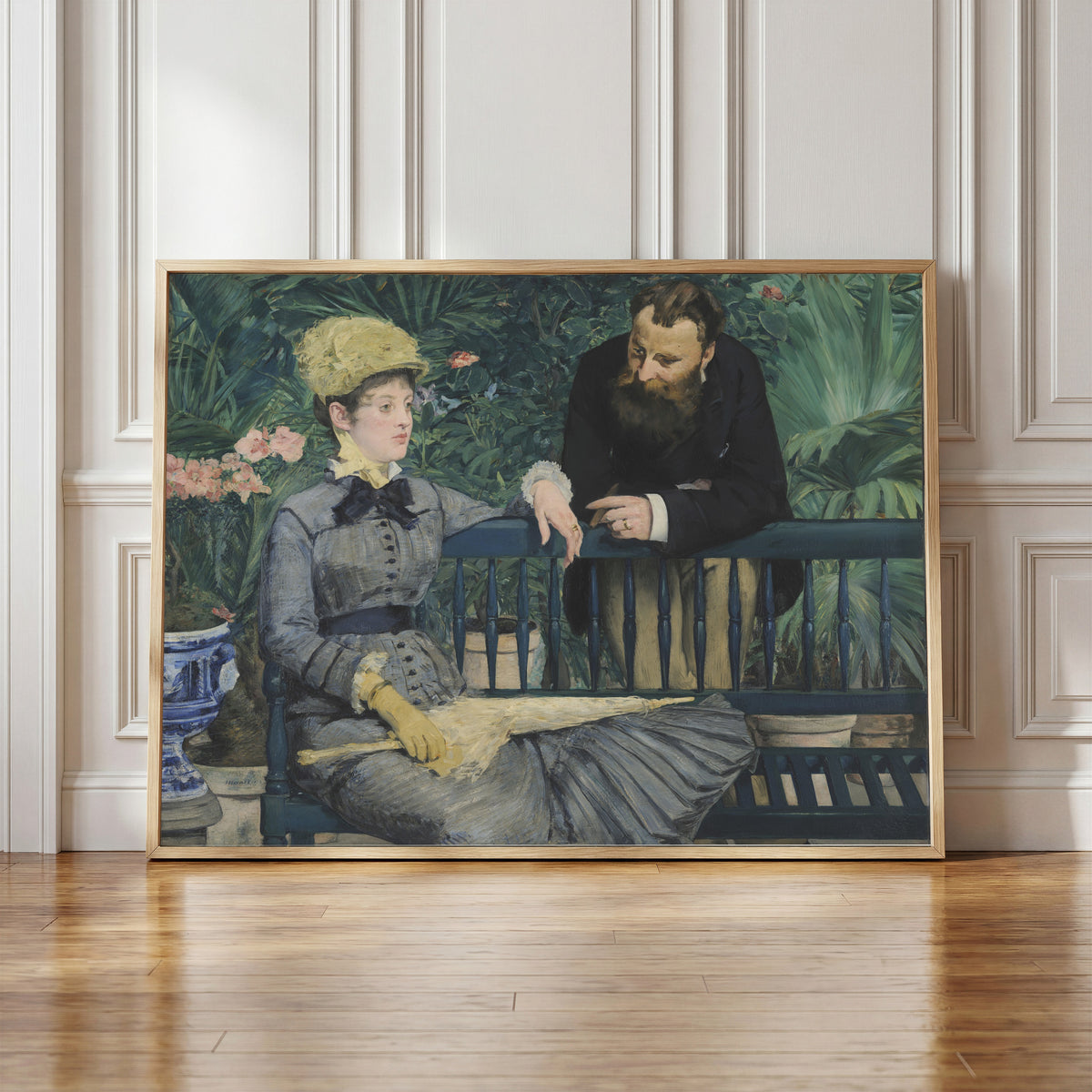 Framed art print of In the Conservatory by Édouard Manet, in a light wood frame leaning against a panelled white wall