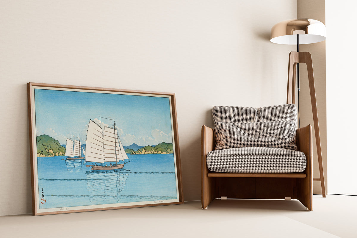 Framed art print of Inland Sea by Kawase Hasui, leaning against a wall beside an armchair and a floor lamp